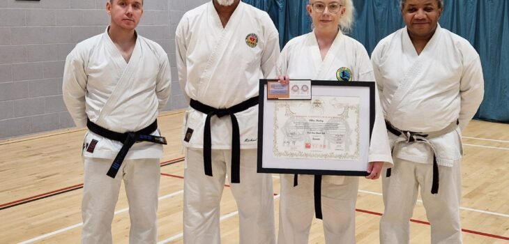 Chloe holding her framed certificate with Sensei Richard, Pat and Mike