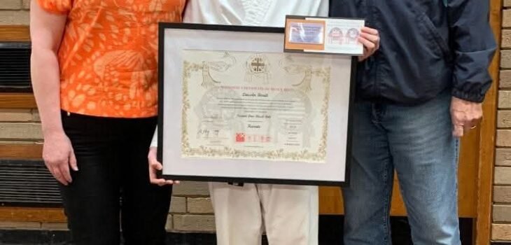 Lincoln holding framed certificate with mum Tracy and grandad Roger